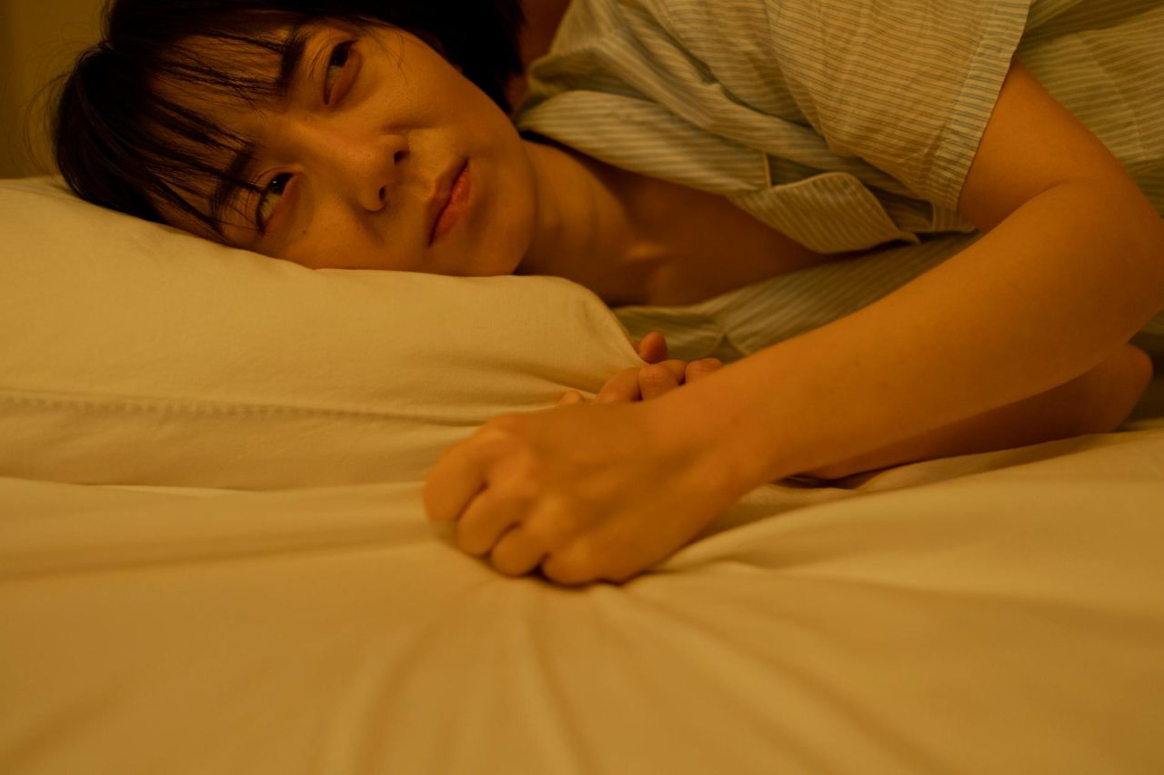 a crying woman gripping the blanket on bed