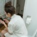 a woman using her cellphone while in the toilet